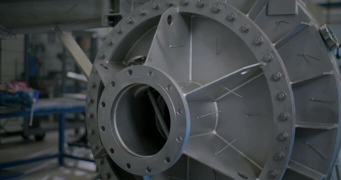 Detail shot of a heavy metallic industrial pump housing flange with bolts and internal structure