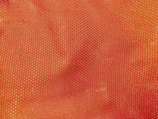 Obraz premium orange textured silk fabric close up reveals intricate geometric weave patterns shimmering under warm studio lighting
