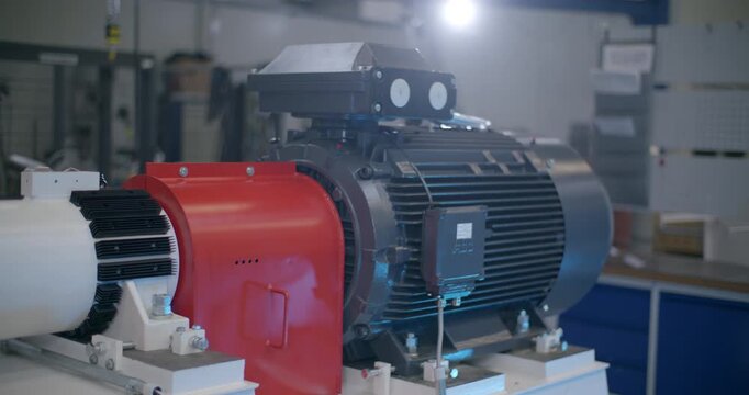 Close up of a large blue industrial electric motor with an orange connection housing