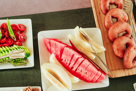 traditional turkish breakfast feast with rich variety on table photos series, fruit plate with watermelon and melon slices, fried dough pisi and cut cucumbers, tomatoes