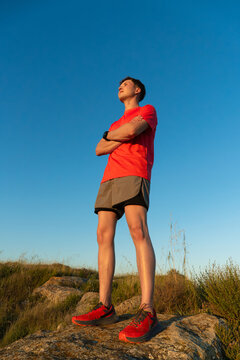 Trail runner standing on rock achieving fitness goal