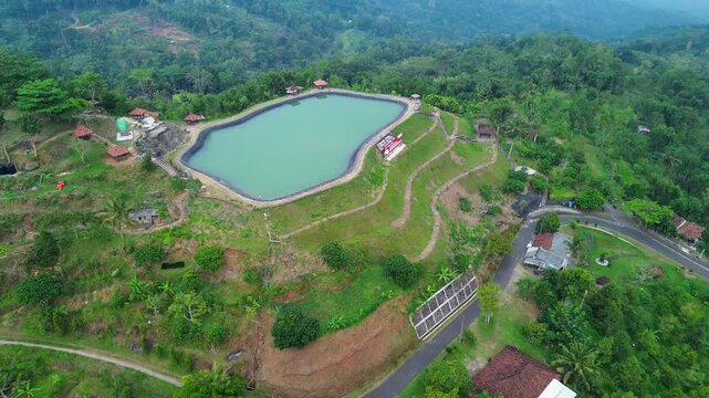 Aerial drone footage of Embung Nglanggeran, a scenic artificial reservoir located in the Ancient Nglanggeran Volcano area, Yogyakarta, Indonesia.