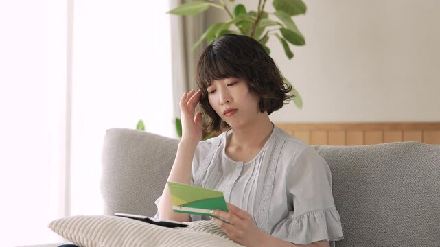 通帳を見ながら家計を考える女性, Woman Reviewing a Bankbook and Household Finances