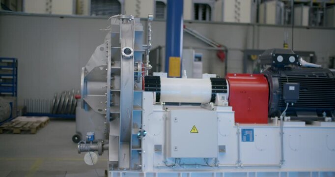 Wide shot of a large industrial machine with a motor in a manufacturing facility