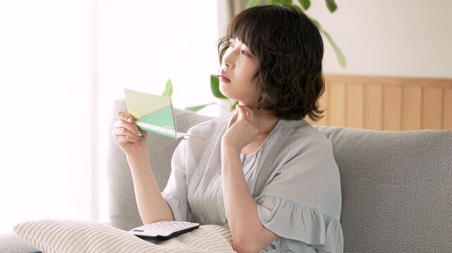 通帳を見ながら家計を考える女性, Woman Reviewing a Bankbook and Household Finances