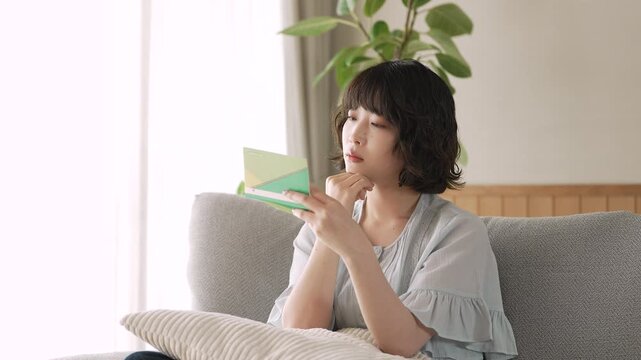 通帳を見ながら家計を考える女性, Woman Reviewing a Bankbook and Household Finances