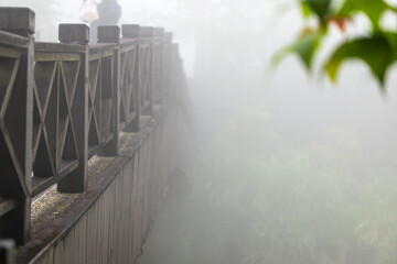 Fototapeta premium Close-up of the handrail of the wooden bridge around Xiangtian Lake, amidst the misty scenery and the travel atmosphere of tourists.