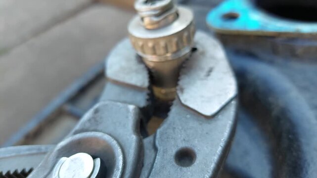 Close-up of water pump pliers loosening a rusty metal nut