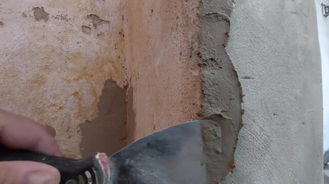 Construction worker applying plaster to an old wall corner with a spatula