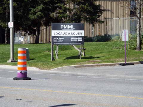 Gatineau,Quebec, Canada &ndash; May 16, 2026: A brick commercial building with large windows and a red door labeled "Mirik" stands behind a grassy lawn at 895 Bd de la Carri&egrave;re.