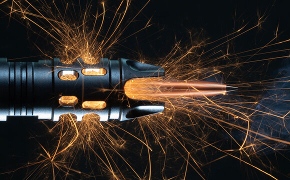 Bullet flying out of a muzzle of a gun with sparks coming out