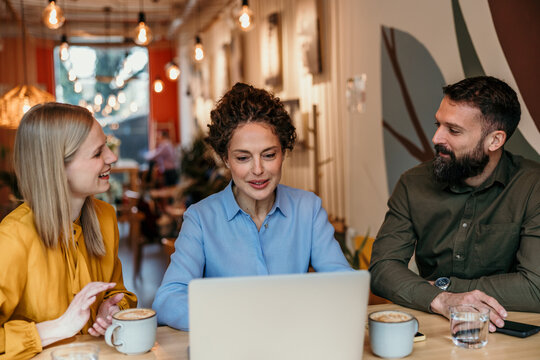 Business colleagues collaborating on laptop in a trendy cafe