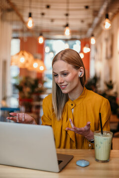 Woman working remotely holding video meeting in cafe