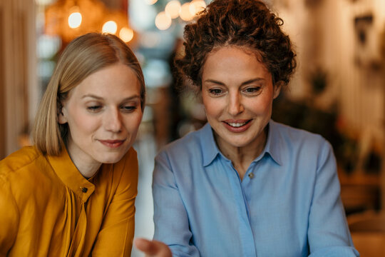 Two women discussing ideas, collaborating and smiling indoors