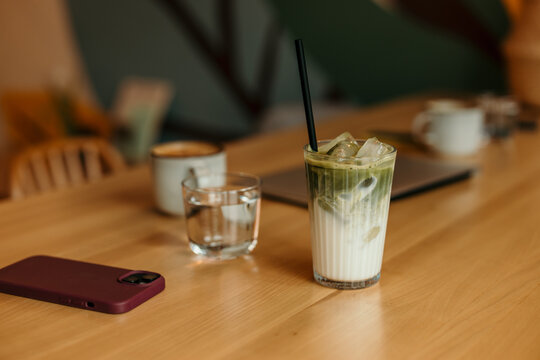 Iced matcha latte with smartphone on cafe table