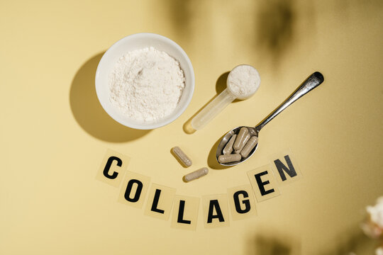 Collagen powder, capsules and scoop with flowers on yellow background