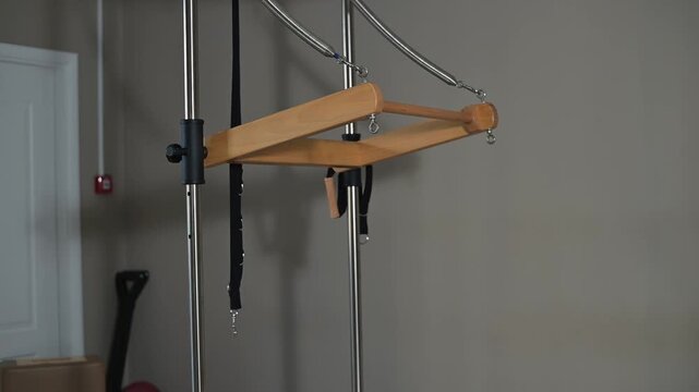 A versatile piece of workout equipment is set up in a home gym environment. The apparatus features adjustable straps and pull mechanisms to support various exercises and fitness workouts