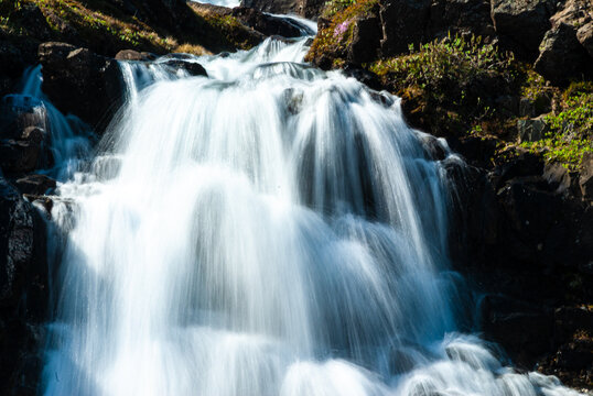 Close up of a cascading waterfall in Iceland with silky flowing water moss covered rocks and dramatic long exposure nature detail