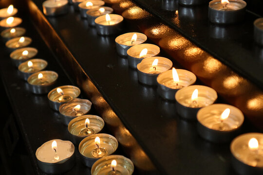Candele votive accese su un candelabro di metallo all'interno di una chiesa per la preghiera e la devozione spirituale