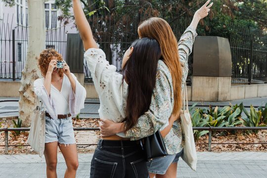 hispanic girls and friends taking a photo with vintage camera in city street, group of latin women together 