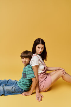 Young mother and her son sit back to back, showcasing comfort and connection in a studio.