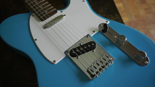 Detailed close-up view of a light blue electric guitar body, showing the strings and pickups