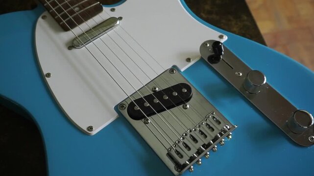 Close-up view of a light blue electric guitar body, showing the strings, pickups, and bridge