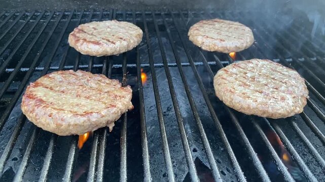 Rohe Burger-Patties auf einem hei&szlig;en Grillrost vor dem Grillen. Authentisches Food-Motiv zu BBQ, Hamburger, Grillparty, Fleisch, Sommer und Outdoor-K&uuml;che.