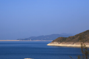 Calm Blue Bay with Rugged Coastline and Distant Mountains © LamQuang