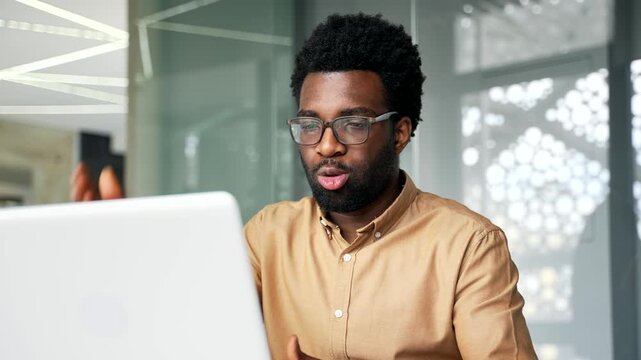 Close up of angry African American boss shouting and lecturing employees during laptop video call. Furious black man executive manager talking aggressively and scolding team on online office meeting.