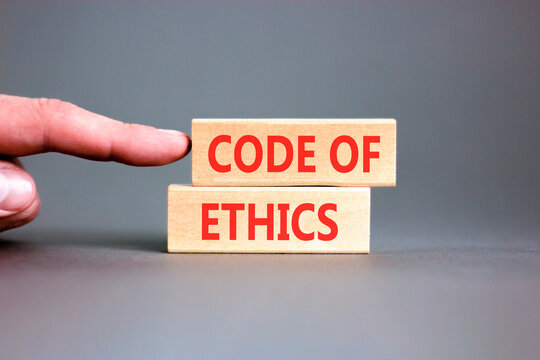 Code of ethics words symbol. Concept words Code of ethics on beautiful wooden blocks. Beautiful grey background. Businessman hand. Business Code of ethics concept. Copy space.