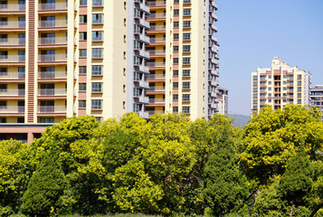 Modern apartment towers above green trees in an urban residential neighborhood © PhungBao