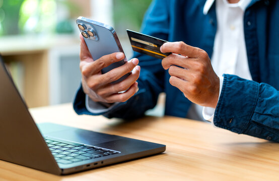 Side view of main focus on left hand of business man hold black credit card and right hand hold mobile phone with concept of online payment with new normal and new trend of lifestyle.