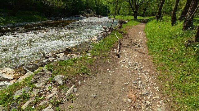 Rapid river flows beside a rocky, grassy trail. Gradac River, Serbia