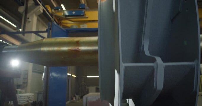 Close up of a metallic impeller rotor mounted on a shaft in an industrial manufacturing workshop
