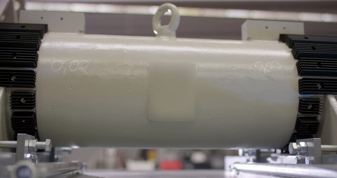 Close up of a cylindrical machine component with numbered markings on a workbench in a factory