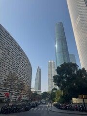 Naklejka premium Wide vertical perspective of a clean city street looking up at contemporary high-rise office buildings and glass skyscrapers under a clear blue sky