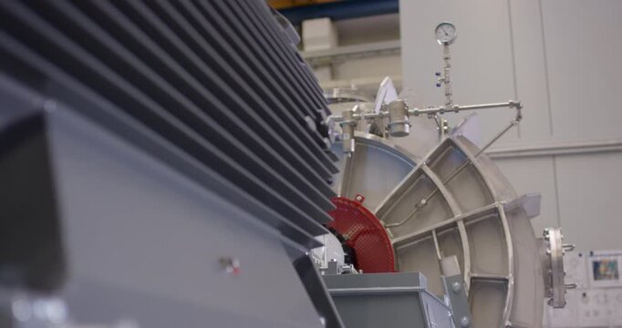 View of a large gray industrial electric motor connected to a metal pump assembly in a factory
