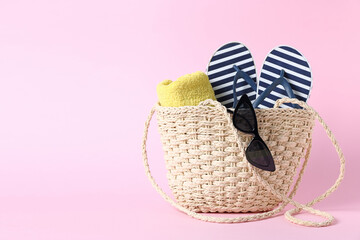 Bag with beach accessories on pink background. Space for text