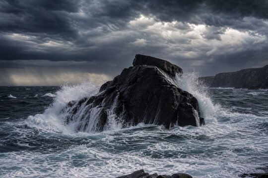 Solid rock unmoved by crashing waves with sea foam in storm lighting.