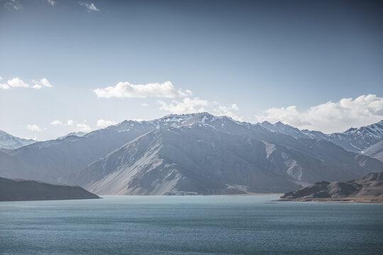Landscape in the Pamir Mountains with a blue lake Yashilkul in the Tien Shan, a panoramic view of the highlands with snow-capped rocky peaks and the blue waters of the lake