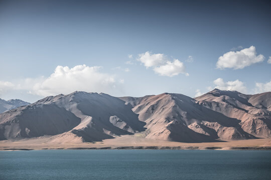 Landscape in the Pamir Mountains with a blue lake Yashilkul in the Tien Shan, a panoramic view of the highlands with snow-capped rocky peaks and the blue waters of the lake