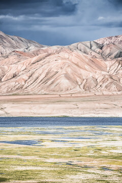 Landscape in the Pamir Mountains in valley with green grassy meadows and pastures, mountain range rises in the Tien Shan Mountains, panoramic landscape for background