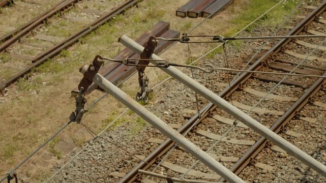 This shows electric wires and current dividers positioned over railway tracks in an open space. The setup is crucial for the operation of electric trains.