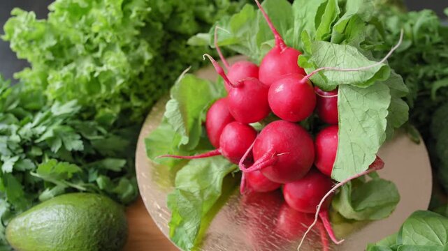 Fresh red radish bunch displayed with leafy greens, parsley, spinach and avocado. Organic radish, root vegetable, crisp produce highlights healthy eating, fresh nutrition, food marketing concepts.