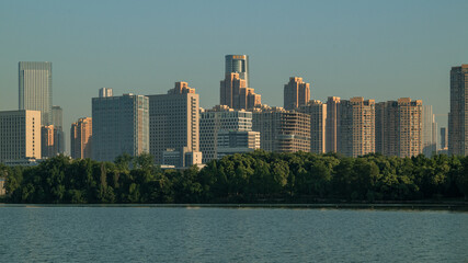 Modern city skyline across a waterfront with trees in evening light © NguyenAnh