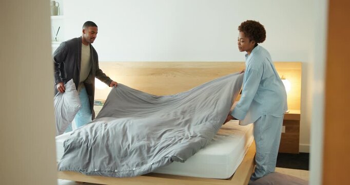 Couple, help and cleaning bedroom in house with pillow, blanket and fresh linen in morning. Happy man, black woman and tidy bed in home with support, playful and teamwork for chores in pyjamas