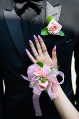 Prom date tuxedo pictured with a pink boutonniere and a corsage of pink roses on high school prom night.  © Jessica