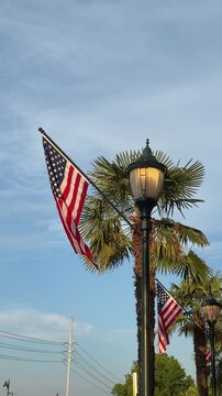 American flag attached to a lamp post blows in the wind against an early evening sky with copy space