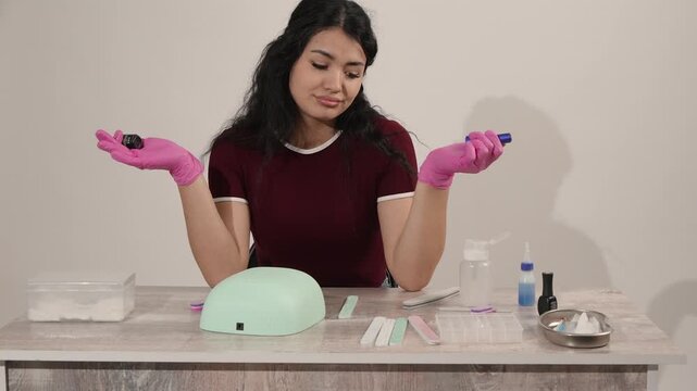 Beautiful young woman choosing nail polish color at a manicure table